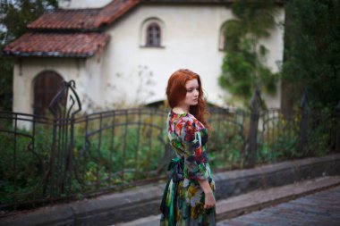 Güzel kızıl saçlı kız Vyborg 'un eski sokaklarında yürüyor.