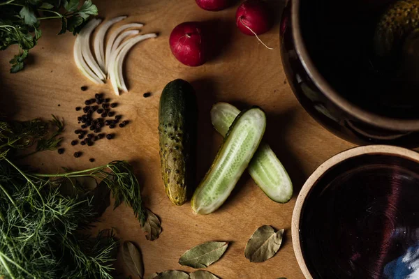Diğer sebzelerle birlikte tahta kesim tahtasının üzerinde salatalık turşusu..