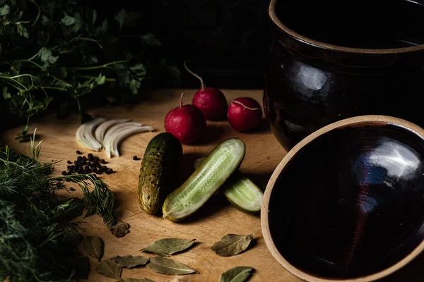 Diğer sebzelerle birlikte tahta kesim tahtasının üzerinde salatalık turşusu..