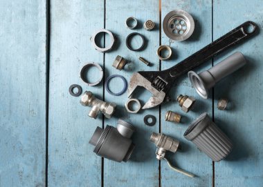 Tesisat için birkaç alet ve yedek parça. Ayarlanabilir anahtar, musluk, hortum ve daha fazlası turkuaz arka planda.