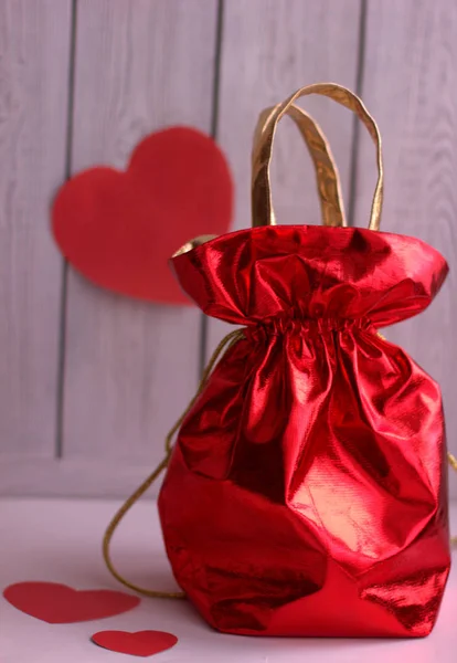 cropped red gift bag on white surface with hearts around. valentine\'s day gift.
