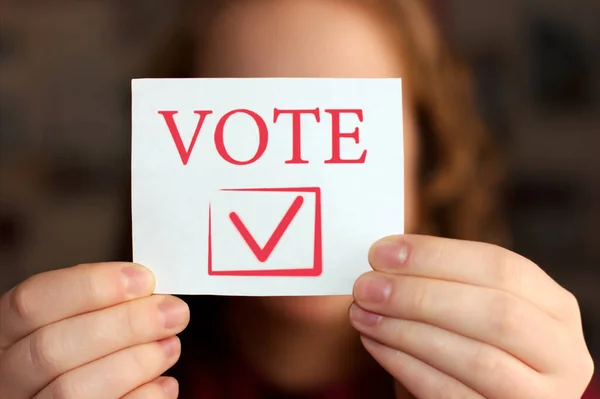 Голосуйте за знак в руках молодой женщины. Концепция голосования или выбора . — стоковое фото