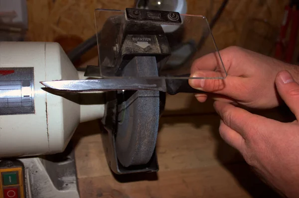 包丁研ぎ器と木製のテーブル、クローズ アップの刃を持つ手 — ストック写真