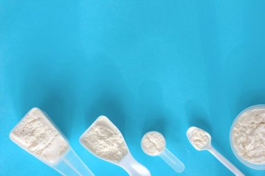 Balık kolajen peptid tozu. Güzellik ve sağlık hizmetleri için farklı kepçe toz kolajen. Moda mavisi arkaplan.