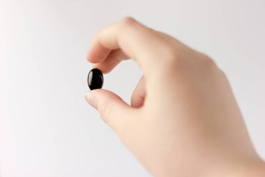 Siyah tıbbi kapsül insan elinde. Hastalıkların, virüslerin, antibakteriyel terapilerin, gıda takviyelerinin tedavisi. Balık yağı kavramı. seçici odak