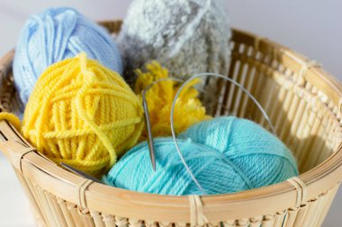 Hasır sepetin içinde renkli yün yumakları ve örgü iğneleri. Hobi ve eğlence için nane ve sarı iplik.. 