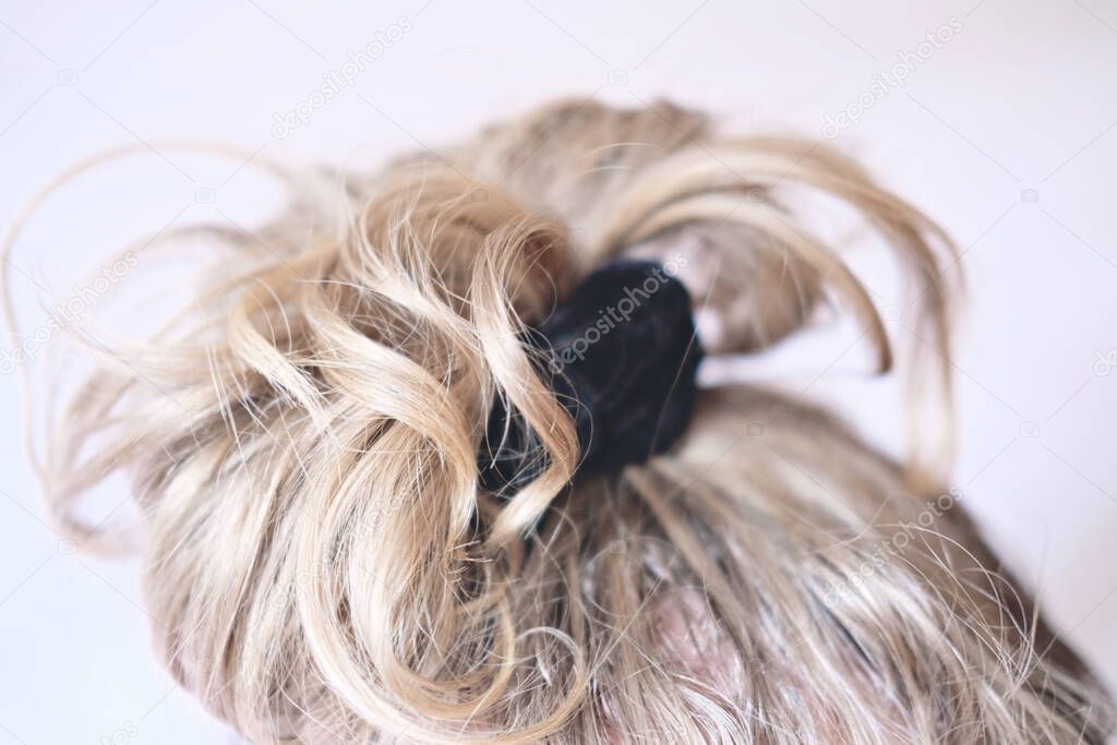 messy bun on the head of a blonde woman. slightly curly hair.