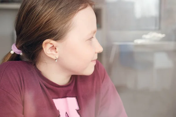 Beautiful teenage girl looking through the window. — Stock Photo, Image