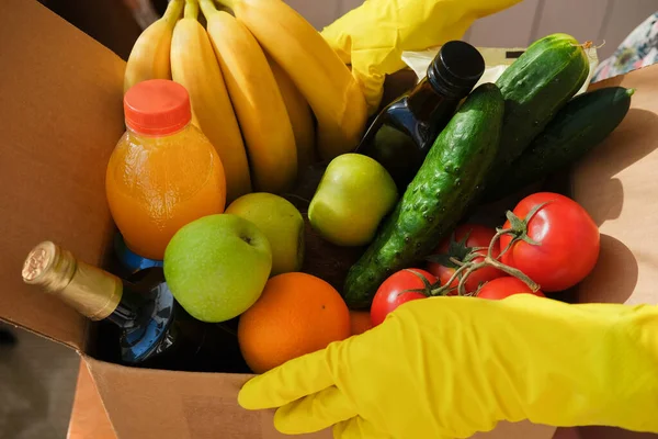 Delivery of a box of vegetables and fruits and ingredients. Healthy food. Shopping box with products. Food delivery coronavirus. Delivery by volunteers during the pandemic.