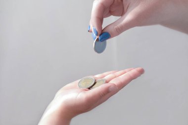 Cep harçlığı konsepti. Bir kadının eli bir çocuğa bozuk para veriyor. Çocuklar, çocuklar ve finans için para. Bağış ve sadaka. ödeme ve transfer para birimi.