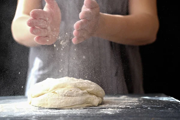 Making dough by hands at bakery or at home. Flour cloud in the air. Royalty Free Stock Images