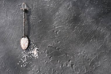Kaşıkta pembe Himalaya tuzu. Gri arkaplanda pembe tuz bulunan klasik kaşık. Çiğ doğal tuz. düz yat