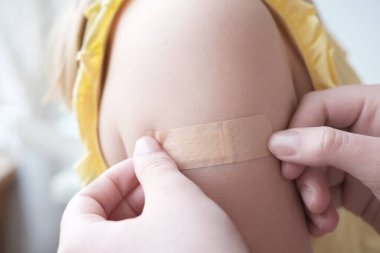Kadın elleri cildindeki küçük bir çizikten sonra çocuğun eline bandaj yapıştırıyor. İlk yardım. Tıbbi konsept. Yakın plan ve Ön görünüm.