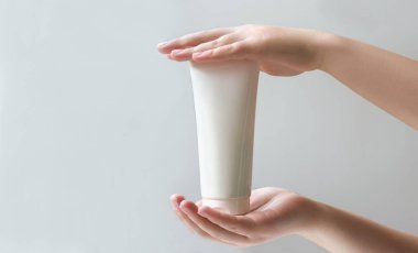 Kozmetik ürün modeli. Kolajen modeli. Kadın, cilt ve saç için krem ya da serum içeren bir tüp tutuyor. Etiket metni için boş yeri olan kozmetik ürünleri için tüp