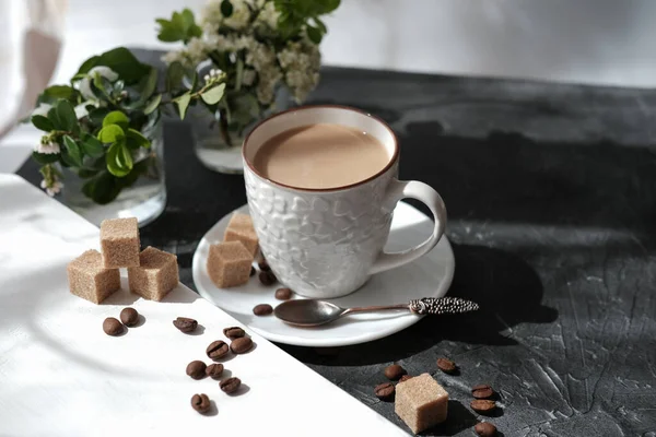 flat white coffee in a cup. brown sugar cubes and coffee beans on a table. flowers and morning sunlight. relax time