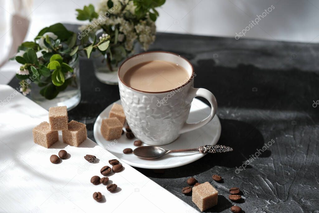 flat white coffee in a cup. brown sugar cubes and coffee beans on a table. flowers and morning sunlight. relax time