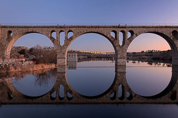 Train bridge across the Adaja rive with the old town of Avila in the background