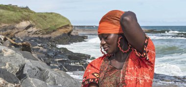 Sekondi-Takoradi Gana 'daki uçurumlarda turuncu elbiseli Afrikalı kadın. Batı Afrika.