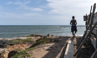 Arka planda Batı Afrika denizi olan Accra şehrinin dışında yüksek irtifada Gana 'dan gelen Afrikalı bir çocuk. 24 Eylül 2019