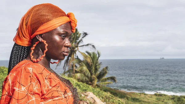 Gana 'lı kadın Takoradi' de kıyıya bakıyor, Batı Afrika, Gana 'da yer alıyor. Afrika 'dan geleneksel renklerin bulunduğu adres ve giysi.