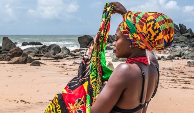 Gana 'lı kadın, Gana Batı Afrika' da bulunan Axim 'in güzel plajında yürüyor. Afrika 'dan geleneksel renklerle adres.
