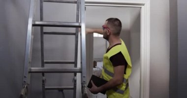 Tamir sonrası çalışmaların kalitesinin incelenmesi. Bir adam kapıların kalitesini kontrol eder..