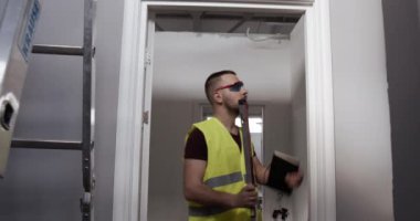 Bir adam, şantiyede çalışan bir işçi. Müfettiş işlerin kalitesini kontrol eder ve not defterine not alır..