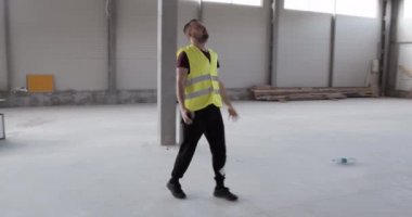 Kızgın bir inşaat işçisi, telefonda sinirli ve kötü konuşuyor, ellerini kaldırıyor ve titriyor..