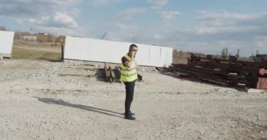 Bir adam, bir inşaat işçisi, şantiyede yürüyen ve gerçekleştirilen işlerin planını kontrol eden bir mühendis..