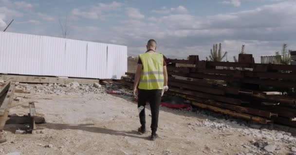 Ένας Εργάτης Μηχανικός Περπατά Στο Εργοτάξιο Σχέδιο Στο Χέρι Και — Αρχείο Βίντεο