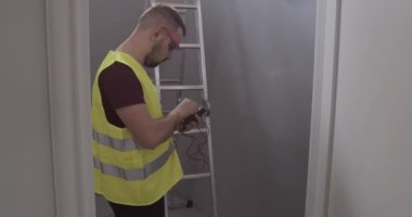 Erkek elektrik mühendisi, bir evin veya inşaatın odasındaki bağlantıları ve voltajı kontrol eder..