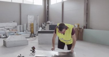 Bir adam, şantiyede çalışan bir işçi. İnşaat malzemelerinin envanteri ve teknik tamamlandı..