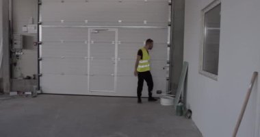 Bir inşaat işçisi şantiyede yürürken bir şey arıyor..
