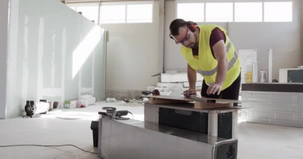 Un homme, un ouvrier de la construction, fait quelques mesures et veut commencer à travailler. Investissements dans la construction .