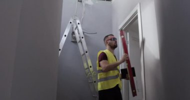 Bir adam, şantiyede çalışan bir işçi. Müfettiş işlerin kalitesini kontrol eder ve not defterine not alır..