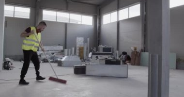 Neşeli ve iyi huylu bir işçi depozitoyu temizlerken süpürgeyle dans eder..