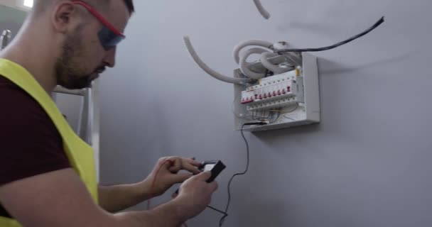 Een Mannelijke Elektrotechnicus Controleert Aansluitingen Spanning Kamer Van Een Huis — Stockvideo