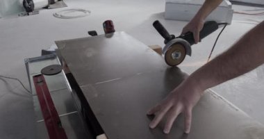 Bir inşaat işçisi depoda çalışıyor ve metal kesme makinesi kesiyor..