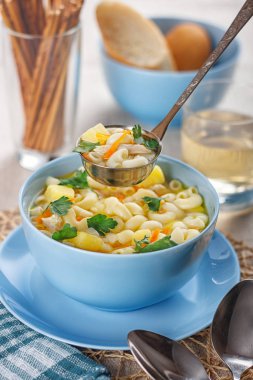 Makarnalı tavuk çorbası ve arka planda limon dilimi.