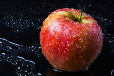 kırmızı çizgili elma, yağmur damlaları ile, ıslak siyah cam üzerinde