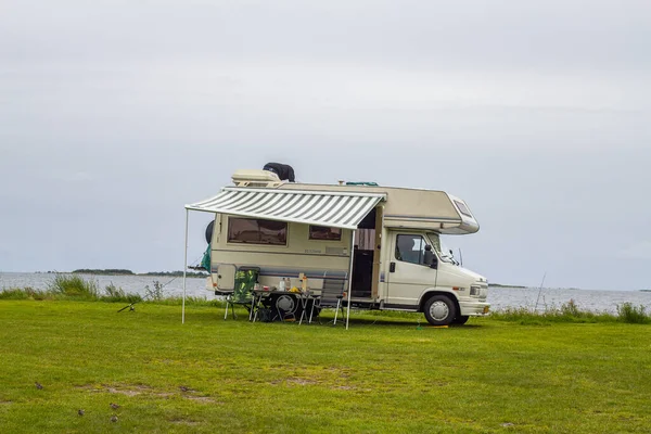 Mobile home on a grassy sea coast on a grey rainy summer day