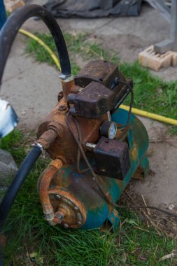 Eski paslı pompa bahçedeki yeşil çimlerde duruyor
