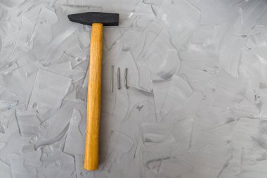 Gri beton arka planda inşaat çekici ve çiviler