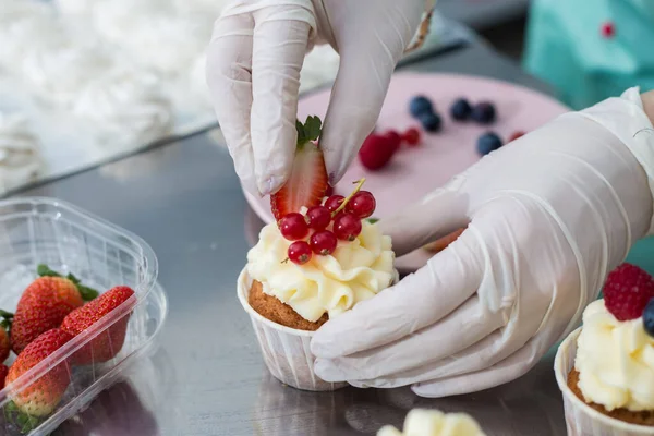 Confeiteiro decorar cupcakes com queijo creme e bagas, close-up . — Fotografia de Stock