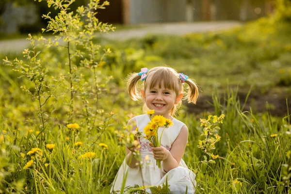 Um retrato de uma menina alegre posando no campo de dentes-de-leão . — Fotografia de Stock