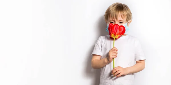 Retrato de menina bonito em máscaras médicas cheirar uma tulipa no branco. Banner — Fotografia de Stock