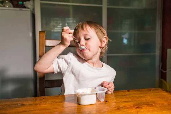 Menina adorável comendo queijo cottage de colher, lanche de leite saudável . — Fotografia de Stock