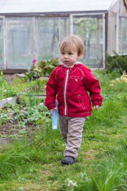 Küçük çocuk bahçede tek başına duruyor.