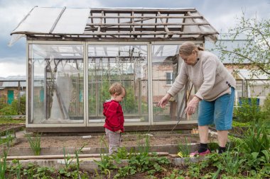 Küçük torunuyla bahçedeki neşeli yaşlı kadın.