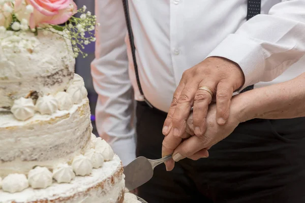 Pareja mayor vestida lujosamente cortando juntos un hermoso pastel de aniversario de boda de tres niveles. Concepto de unión y amor eterno. Enfoque selectivo . — Foto de Stock